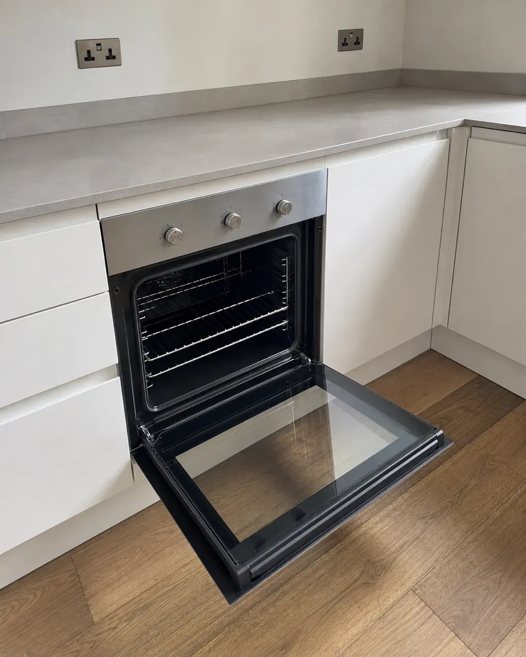 An open oven door in a Clapham kitchen showing a completely clean empty cavity with the racks back in place and the inner glass clear
